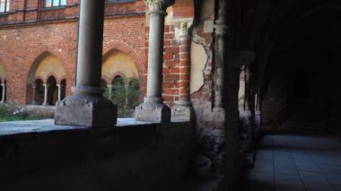 Riga Katedrali 'nin gölgeli koridoru ve kırmızı tuğlalı cephesi avlu bölgesinden görülebiliyor. Riga Dome (Letonya) Romanca, erken dönem Gotik, Barok ve Art Nouveau eserlerini birleştiren bir binadır.