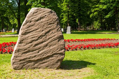 Çiçek tarlalarında manzaralı bir yaz parkında desenli bir yüzeyi olan büyük bir anıt taşı boş..
