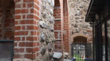 Dobele 'deki (Letonya) ortaçağ kalesinin yenilenmiş duvarları, çağdaş metal ve cam mimari özelliklere sahip tarihi tuğla ve taş duvarların bir karışımını sergiliyor..