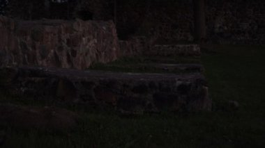 Az aydınlatılmış ortaçağ şatosu kalıntıları ve antik taş duvarcılık temelleri. Alacakaranlıkta yakalanan bu sakin sahne, tarih, gizem ve zamansız çürümeyi çağrıştırıyor..