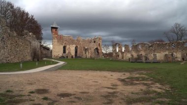 Tarihi Dobele Kalesi 'nin panoramik bir sahnesi sonbaharın sonlarında harabeye döndü. Yenilenmiş taş duvarlar ve yenilenmiş bir merkez bina dramatik, bulutlu bir gökyüzünün altında duruyor, antik bir ihtişamı çağrıştırıyor..