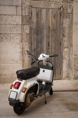 Akdeniz tarzı klasik sahne, taş duvarda eski ahşap kapı ve scooter.
