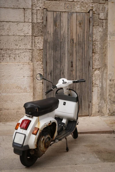 Akdeniz tarzı klasik sahne, taş duvarda eski ahşap kapı ve scooter.