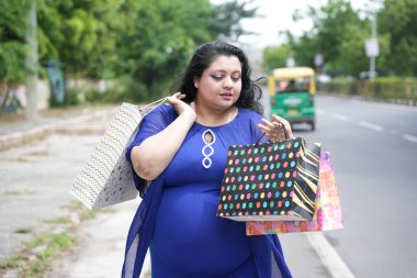 Genç Hintli artı boyunda bir kadın sokakta alışveriş torbaları tutuyor. Şişman kadın alışveriş yapıyor..