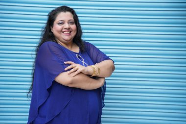 Mavi arka planda izole bir şekilde duran genç Hintli artı boyut kadın portresi..