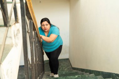 Şişman Hintli kadın kendini iyi hissetmiyor, merdivenleri çıkarken nefes alamıyor. Sağlık Hizmetleri Konsepti.