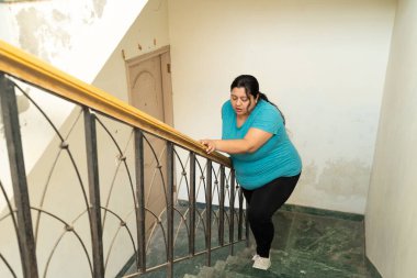 Şişman Hintli kadın kendini iyi hissetmiyor, merdivenleri çıkarken nefes alamıyor. Sağlık Hizmetleri Konsepti.