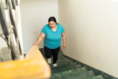 Şişman Hintli kadın merdivenleri tırmanıyor. Ayrıca beden ölçülerinde kadın egzersizi, sağlık sigortası kavramı..