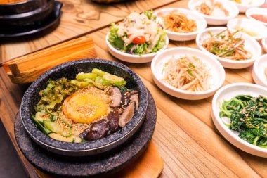 Bibimbap siyah ısıtılmış taş bir kase, Kore geleneksel bibibimbap - sebzeli pilav sığır eti, yumurta ve turşu, masaya konmuş sıcak Japon yemeği.