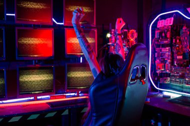 Kazandım. Mutlu genç oyuncu çevrimiçi bilgisayar oyunu oynuyor. Turnuvayı kazanmak için elini kaldırıyor. Oyun kulaklığı takan genç kadınlar evlerinde online video oyunu oynuyorlar.