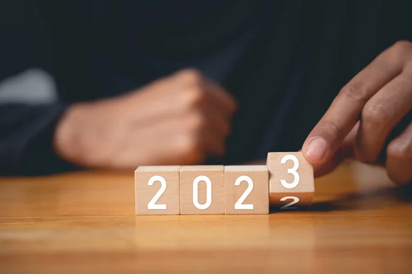 Happy New Year 2023. Businessman flips wood cubes block number 2 to 3 for new years 2023 setting target plan business goal, Start success business
