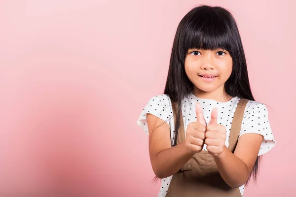 Asian little kid 10 years old showing thumbs up at studio shot isolated on pink background, Portrait of happy child girl positive smiling show finger for good gesture