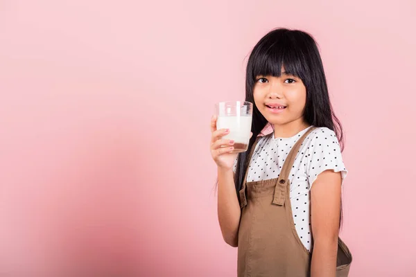 アジアの小さな子供10歳の笑顔を保持ミルクグラスドリンク白ミルクでスタジオショットピンクの背景に隔離されました 幸せな子供の女の子の日常生活医療医学食品 — ストック写真
