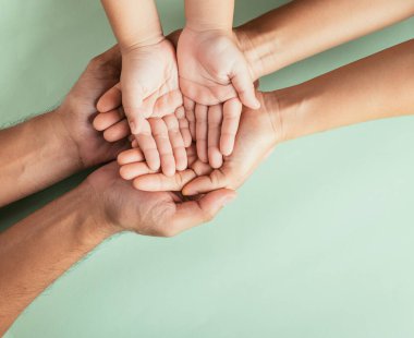 Üst düzey ebeveynler ve küçük çocuklar el ele tutuşuyorlar. Stüdyo görüntüleri yeşil arka planda izole edilmiş, aile evi, çocukları yetişkin annelerin ellerine teslim etmek, destek olmak, aile günü konsepti.