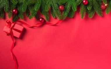 Noel tatili arkaplanı hediye kutusu süslemeleri üst görünüm köknar ağacı dalları ve kırmızı masa arkaplanındaki Xmas süslemeleri.