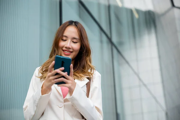 アジアのビジネスマンスマートフォンの通勤作業をテキスト化彼女は午前中に彼女のオフィスビルの近くを歩いて 美しいビジネス女性は笑顔は街の通りの都市に携帯電話の屋外歩行を保持 — ストック写真