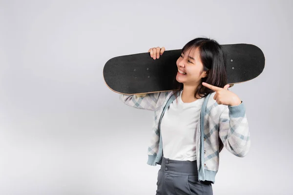 笑顔幸せな女性は肩の上にスケートボードを保持し ボードに指を指す 幸せなアジアの美しい若い女性励起ホールド手ロングボード スタジオショットコピースペースと白の背景に隔離 — ストック写真