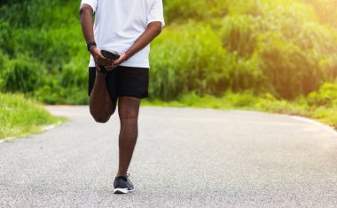 Kapatın Asyalı genç atlet spor koşucusu siyah adam kol saati takın bacaklarınızı ve dizlerinizi esnetin açık hava sokak sağlık parkında koşmadan önce spor konseptinden önce sağlıklı egzersiz