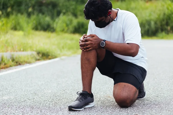 在室外街道健康公园跑步时 亚洲年轻的运动健将黑衣人身穿手表 手牵着膝盖疼痛 运动理念对健康的伤害 — 图库照片