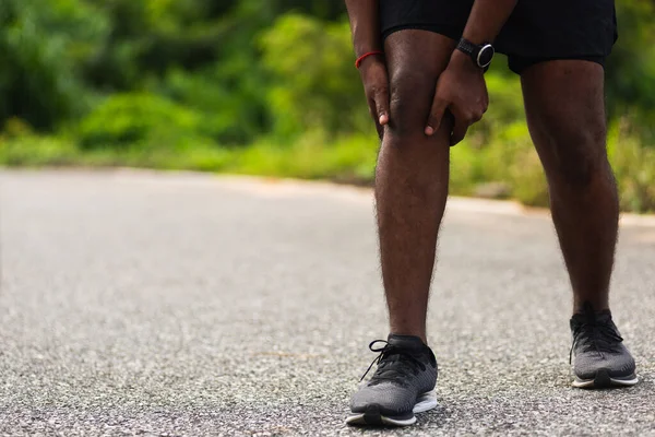 亚洲年轻的运动健将黑衣人戴着看台 在室外街道健康公园跑步时手牵着膝盖疼痛 运动理念对健康造成的伤害 — 图库照片