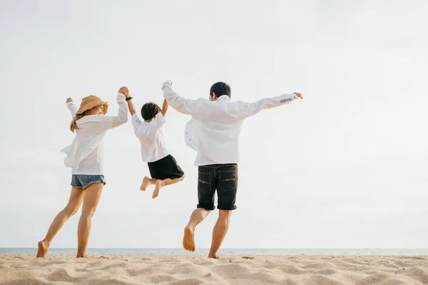 家族のアウトドア活動 家族の母親 父と息子が手を取り合って夜明け時に空中でジャンプするハッピーアジアの家族は 休日の夏休み旅行でビーチで一緒に楽しみを持っています — ストック写真