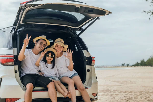 Tourism Day. Family having fun in summer vacation on beach show V-sign finger. Parents and kid family travel in holiday at sea beach. Father, Mother and daughter enjoying road trip sitting on back car