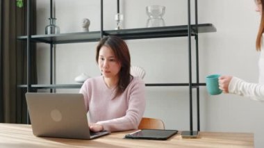 Asyalı orta yaşlı bir kadın ve genç bir kız bilgisayardan alışveriş yapıyor, anne ve genç bir kız ev bilgisayarına bakıyor, mutlu bir aile birlikte çalışıyor.