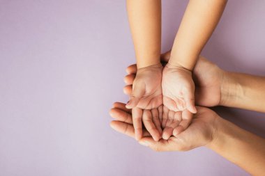 Üst düzey ebeveynler ve küçük çocuklar el ele tutuşuyorlar. Stüdyo çekimleri pembe arka planda izole edilmiş, aile evi, çocukların eline yetişkin anne eli, destek, aile günü konsepti.