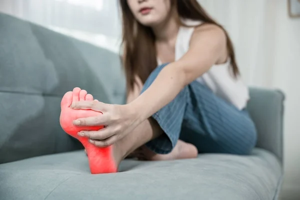 亚洲年轻女子坐在沙发上按摩脚 伸展肌肉 有疼痛的症状 漂亮的女性问题 家里有脚 脚踝受伤 医疗保健和医疗 — 图库照片