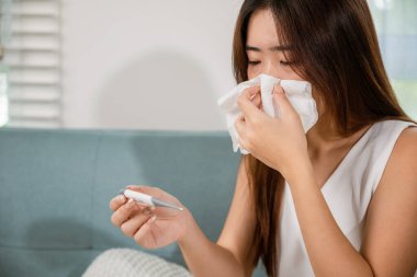 Hasta kadının ateşi var. Evdeki termometreyle ateşini ölçüyor. Grip, ateş, sağlık ve tıbbi konseptten muzdarip genç bir kadın.