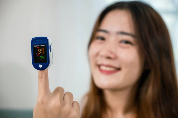 아시아인젊은 여성은 의료용 장치를 사용하여 거실에 소파의 포화를 측정하고 코로나 — 스톡 사진
