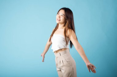 Mutlu kadın tek başına gülümsüyor özgürlük, Asyalı genç kadın kolları güneş ışığına açık çekim için mavi arka planda izole edilmiş.