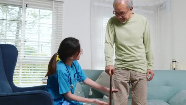 アジアの医師は 杖で痛みの症状について高齢者の質問と説明 膝や足をチェック若い女性看護師膝の痛みに苦しんでいる高齢男性患者の手術後 — ストック動画