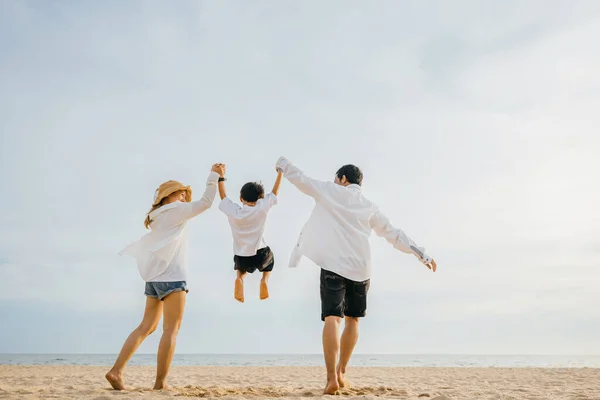 家族の母親 父と息子が手を取り合って夜明けの時間に空中でジャンプし 家族の屋外活動 幸せなアジアの家族の人々はビーチで一緒に健康的なライフスタイルを楽しんでいます 休日の休暇 — ストック写真