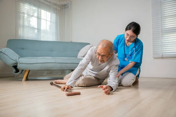 老年残疾男子 手持手杖 倒在地板上 在养老院照顾年幼的助手 亚洲老年男子倒在地板上 女护士前来帮忙照顾 — 图库照片