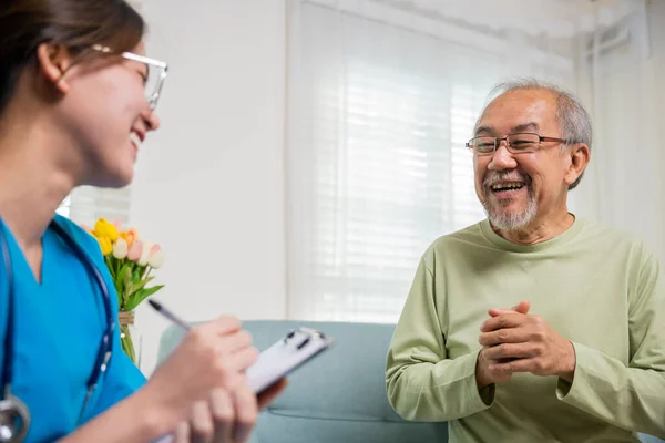 老年男子在家中带医生讲述健康问题 亚洲年轻护士在家中与生病的老年男子交谈时填写处方剪贴板 以及保健和医疗概念 — 图库照片