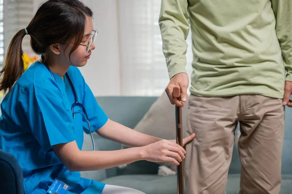 亚洲医生用手杖询问和解释老年男子疼痛症状 老年老年男子膝部疼痛患者术后检查膝部和腿的年轻妇女护士 — 图库照片