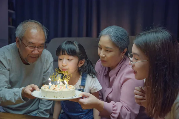 幸せなアジアの家族の祖父母と母は孫娘のケーキで誕生日パーティーを楽しむ夜に家でろうそくを吹いて 誕生日の驚きのコンセプト — ストック写真