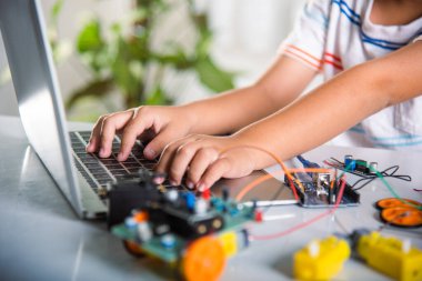 Asyalı çocuk, Arduino robot arabası için dizüstü bilgisayarla kodlama ve programlama öğreniyor, küçük çocuk öğrenciler, araba oyuncağıyla bilgisayar kodları yazıyorlar, STEAM eğitim teknolojisi kursu öğreniyor.