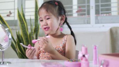 Asyalı sevimli küçük kız makyaj yapıyor aynaya ve yanağa bakıyor pudra için pofuduk fırça, kadın olmak için etkinlik öğreniyor, mutlu çocuk güzel makyaj yapıyor kozmetik oyuncağıyla.