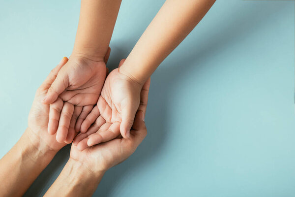 Closeup top view family hands stack palms studio shot isolated on blue background, parents and kid holding empty free space on hand together, Gesture sign of support and love, Family and parents day