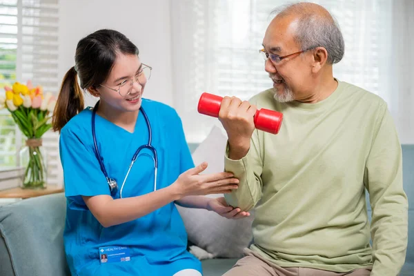 亚洲护士理疗师帮助老年人在养老院提起哑铃 年轻护士提供护理支持 利用哑铃锻炼训练老年人坐在沙发上 医疗保健医疗 — 图库照片