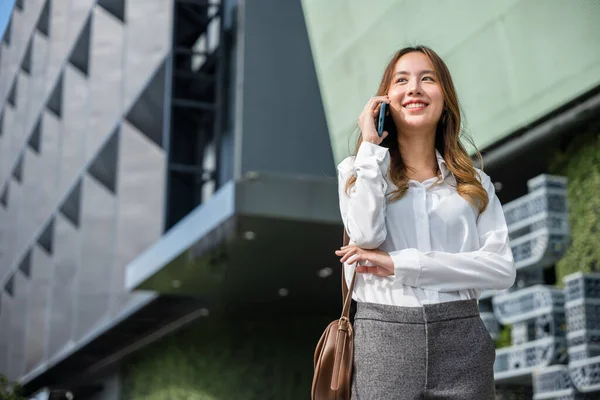 Young lawyer business woman walking street outdoor calling and talking on mobile phone with client, happy people smile talk on smartphone, cellphone communication