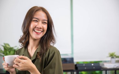 Asyalı genç bir kadının portresi sabah poz verirken sıcak kahve ya da çay fincanı tutarken beyaz porselen kupa taklit edilirken mutlu, güzel bir kadının evde uyandıktan sonra dinlenmesi, yaşam tarzı...