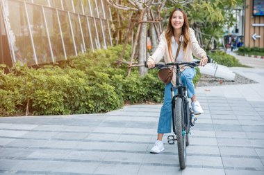 Happy Asian beautiful young woman riding bicycle on street outdoor near building city, Portrait of smiling female lifestyle using bike in summer travel means of transportation, ECO friendly