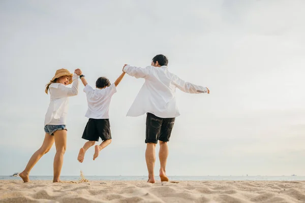快乐的亚洲家庭 快乐的生活在海滩上 健康的生活在一起 家庭的母亲 父亲和儿子牵着手 黎明时分在空中跳跃 家庭户外活动的概念 — 图库照片