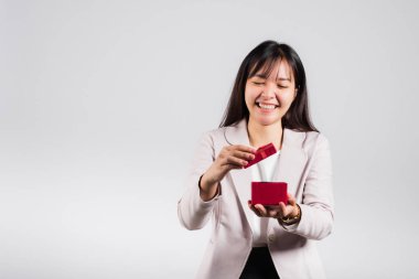 Gülümseyen kadın özgüveni, avuç içi izole edilmiş beyaz arka planda kırmızı bir hediye kutusu açıyor, sürpriz doğum günü veya Noel günü ve sevgililer günü, Asyalı mutlu portre güzel genç bayan stüdyo resmi, kopyalama alanı