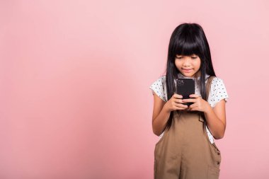 Asyalı çocuk 10 yıl boyunca cep telefonunu stüdyoda sosyal medya için kullanmaktan keyif aldı. Pembe arka planda izole edilmiş, mutlu çocuk kız yaşam tarzı akıllı telefon kullanarak, arkadaşınla mesajlaşarak.