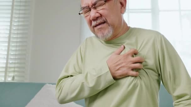 アジアの高齢者は 自宅で一人で心痛に苦しんで先天性疾患を持っています 高齢者の悪い痛みの手は心臓発作を持って胸に触れる 高齢者の退職健康問題不健康な病気 — ストック動画