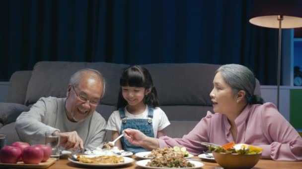 아시아 부모와 거실에서 식사를 할머니와 손녀가 식탁에서 식사를 밤에는 집에서 — 비디오